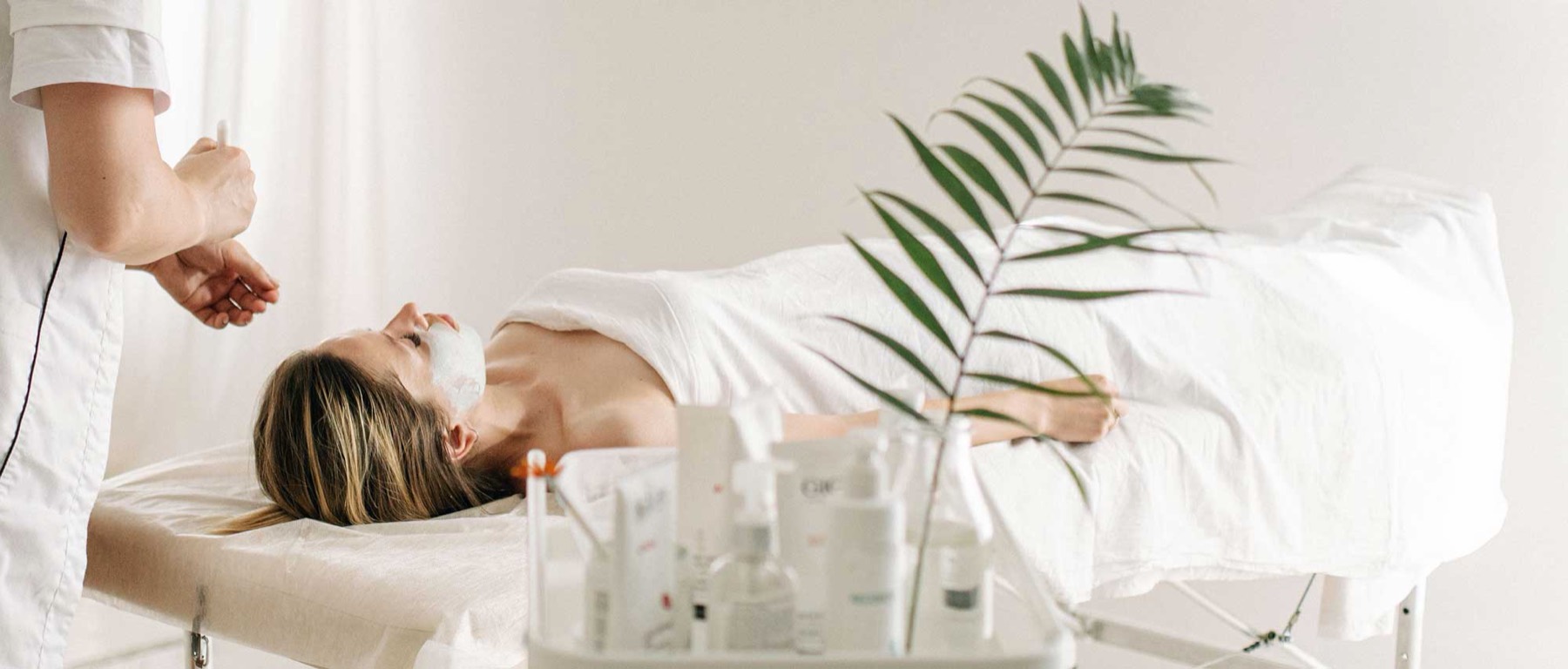 A beauty therapist treating a client in a bright, calm studio